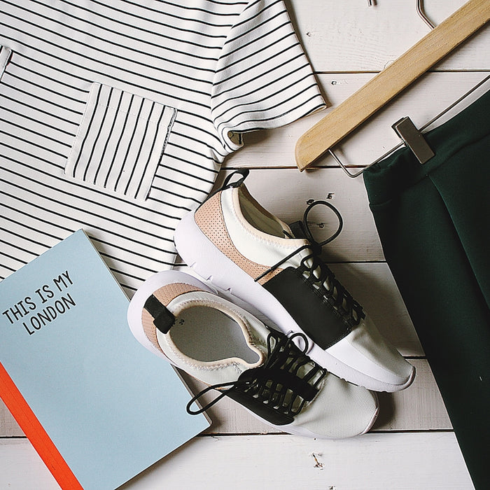 pair of white-and-black low-top sneakers near black skirt on brown clothes hanger top view photography