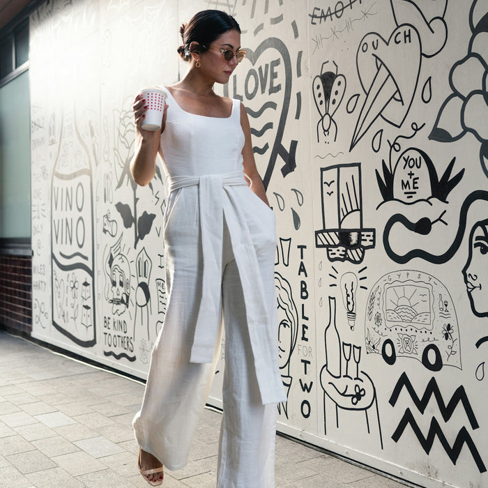 woman holding cup walking beside wall