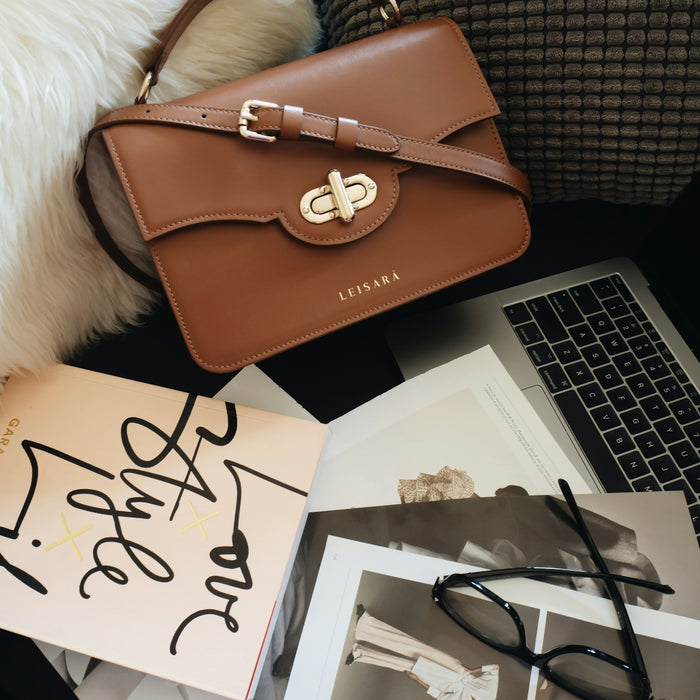 brown leather handbag beside macbook pro