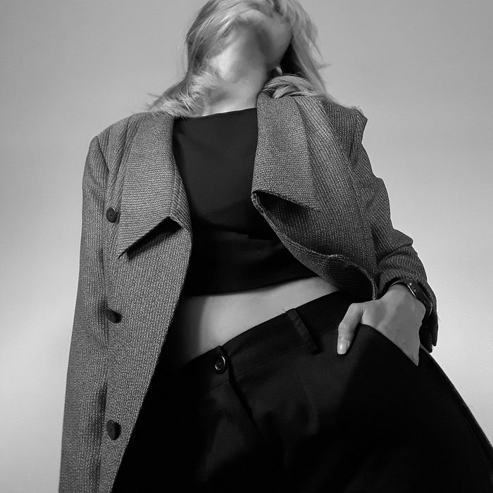 woman in black blazer covering her face with gray scarf