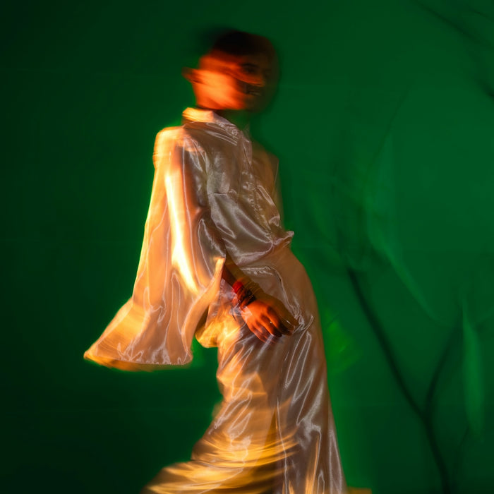 A blurred figure in white against a green backdrop.