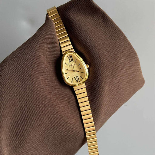 Gold wristwatch on a brown fabric background