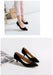 Black high-heeled shoes on a white background with a person wearing them.