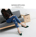 Woman sitting on a gray sofa wearing a striped sweater, ripped jeans, and green shoes, with a beige bag beside her.