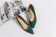 Green high-heeled shoes on a white surface with a magazine in the background