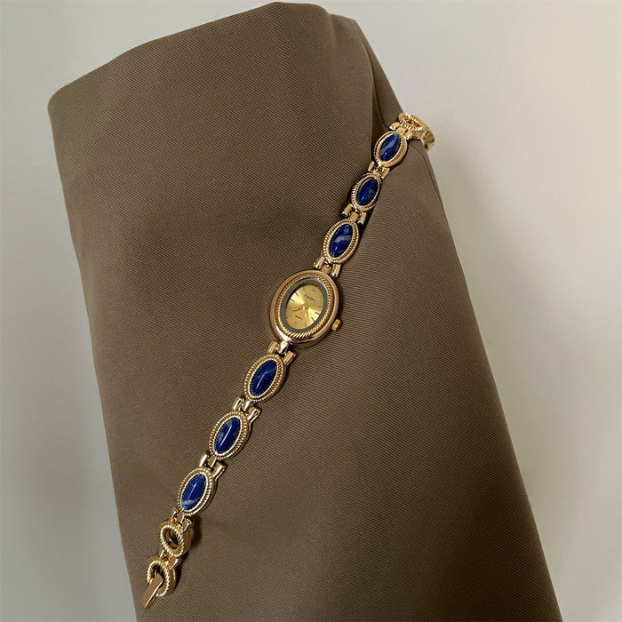 Gold bracelet with blue stones on a brown fabric background