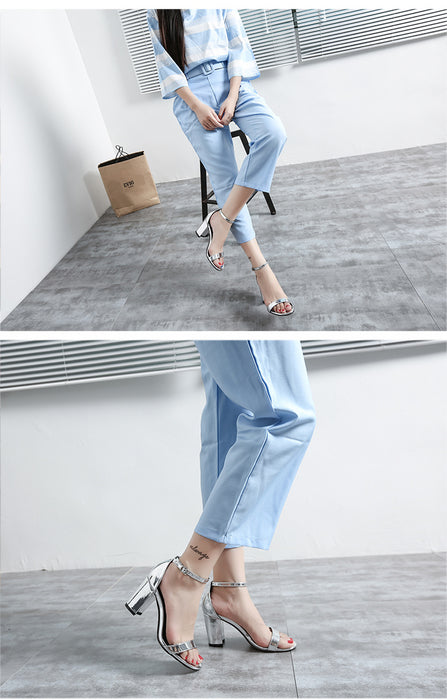 Person wearing light blue jeans and high-heeled shoes in a minimalistic setting.
