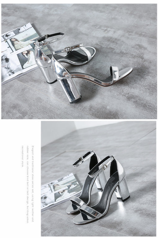 Silver high-heeled shoes on a gray concrete floor with a magazine.
