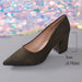 A single pointed-toe high-heeled pump in dark olive-brown suede, shown on a gray surface with a colorful sequined backdrop. A measurement bracket and text indicate a 7 cm heel height.