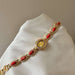 Gold bracelet with red stones on a white cushion