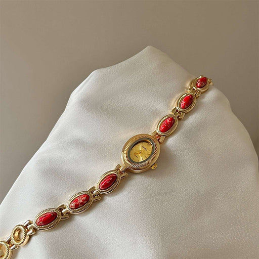 Gold bracelet with red stones on a white cushion