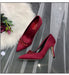 Red high-heeled shoes with embellishments on a decorative background