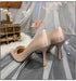 Beige high-heeled shoes with decorative elements on a soft, blurred background