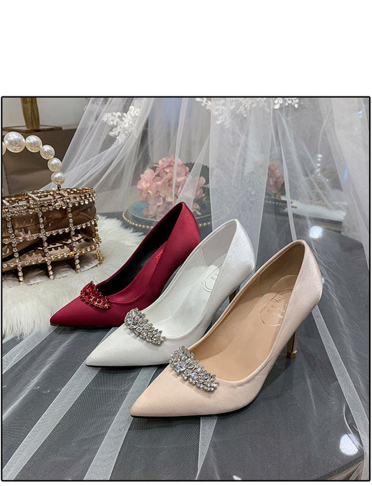 Two high-heeled shoes, one red and one beige, with decorative elements on a reflective surface.