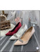 Two high-heeled shoes, one red and one beige, with decorative elements on a reflective surface.