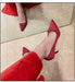 Red high-heeled shoes with embellishments worn by a person in red pants on a light-colored floor.