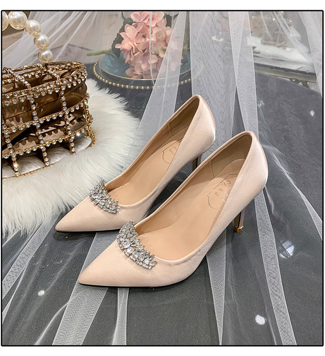 Beige high-heeled shoes with crystal embellishments on a decorative background