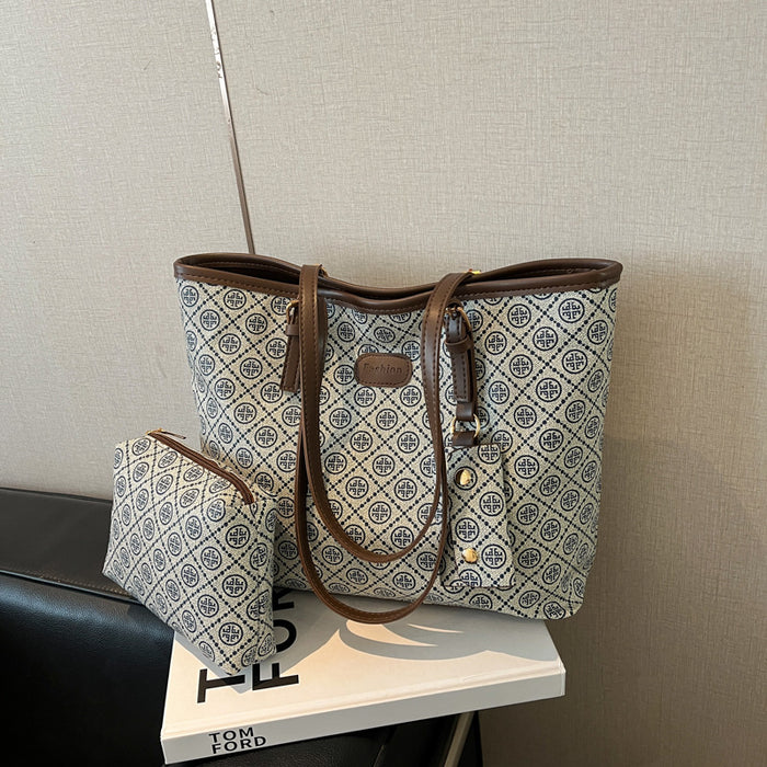 A tote bag with a brown leather trim and a matching zip pouch, both featuring a beige and blue geometric monogram pattern, displayed on a white book.
