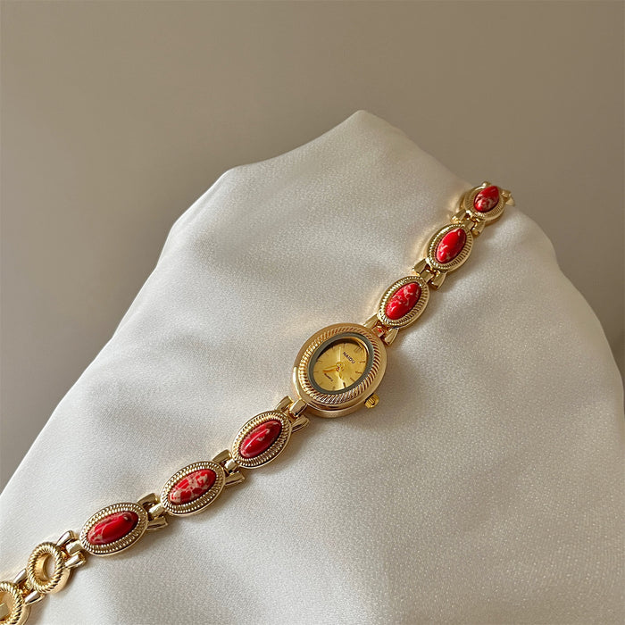 Gold bracelet with red stones on a white cushion