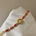 Gold bracelet with red stones on a white cushion