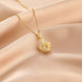 Gold crown-shaped pendant necklace on a soft pink fabric background
