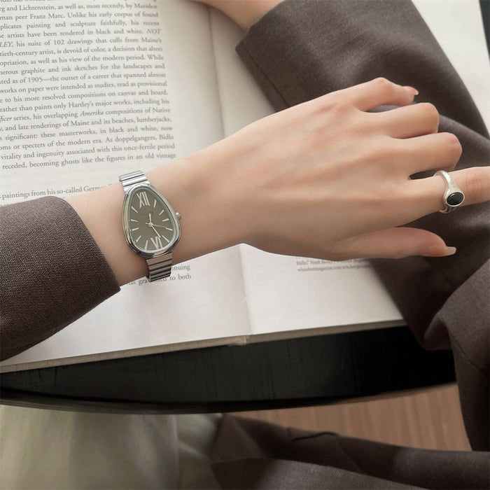 Hand wearing a watch on an open book with a blurred background