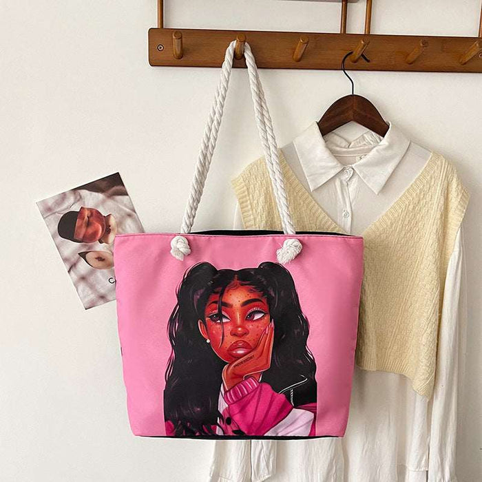 Pink tote bag with a graphic design of a woman's face, hanging on a wooden hook with clothes in the background.