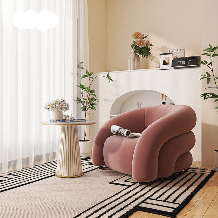Modern living room with a pink armchair, side table, and decorative elements.