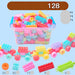 A clear plastic box filled with colorful oversized building blocks, with several toy trains and loose blocks displayed around it on a light blue background. Chinese text at the top and bottom indicates the set contains about 128 large-grained blocks and lists included accessories.
