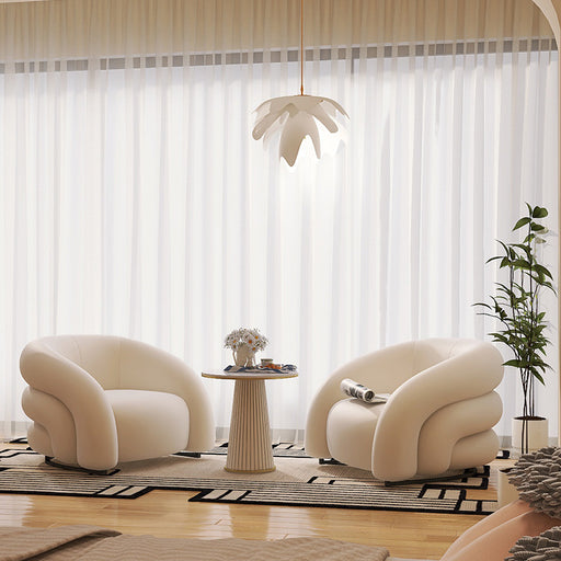 Modern living room with two cream-colored armchairs, a small table, and a plant.