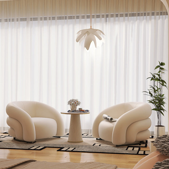 Modern living room with two cream-colored armchairs, a small table, and a plant.