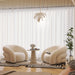 Modern living room with two cream-colored armchairs, a small table, and a plant.