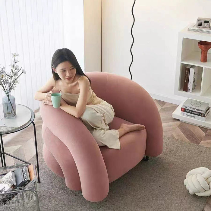 Woman sitting on a pink inflatable chair in a modern living room.