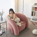Woman sitting on a pink inflatable chair in a modern living room.