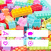 A pile of colorful plastic building blocks in pastel and bright shades, with four white text badges showing Chinese selling points like no odor, no hair-like tips, easy interlocking, and sufficient quantity.