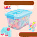 A clear plastic storage box filled with colorful building blocks, shown on a pale pink background with Chinese promotional text. The box has a light blue lid and handle, and the blocks inside are pastel pink, blue, green, yellow, and purple.