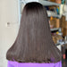 Person with long, straight, dark brown hair in a salon setting.