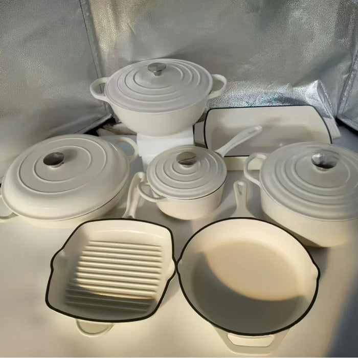 Set of white cookware with lids on a reflective surface