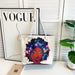 Tote bag with a colorful design of a woman with a starry afro, placed on a surface with a 'Vogue' magazine in the background.