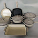 Set of beige cookware including pots, pans, and lids on a gray background