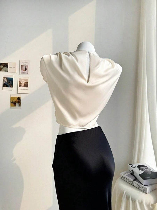 Mannequin wearing a white top and black skirt against a neutral background