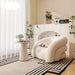 Modern living room with a white armchair, decorative table, and plants.