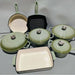 Set of green and beige cookware including pots, pans, and lids on a light gray background.
