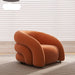 Orange armchair on a textured floor with light-colored blinds in the background