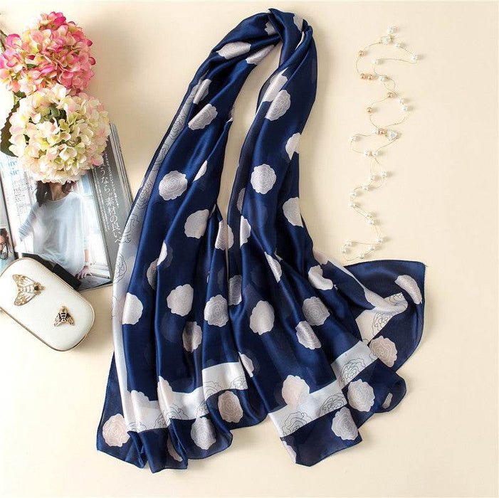 Navy blue scarf with white polka dot pattern on a light surface with decorative items.