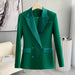 Green blazer on a hanger against a neutral background