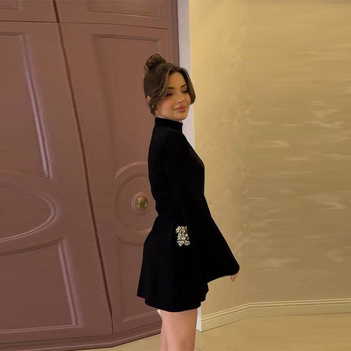 Woman in a black outfit standing in front of a pink door.