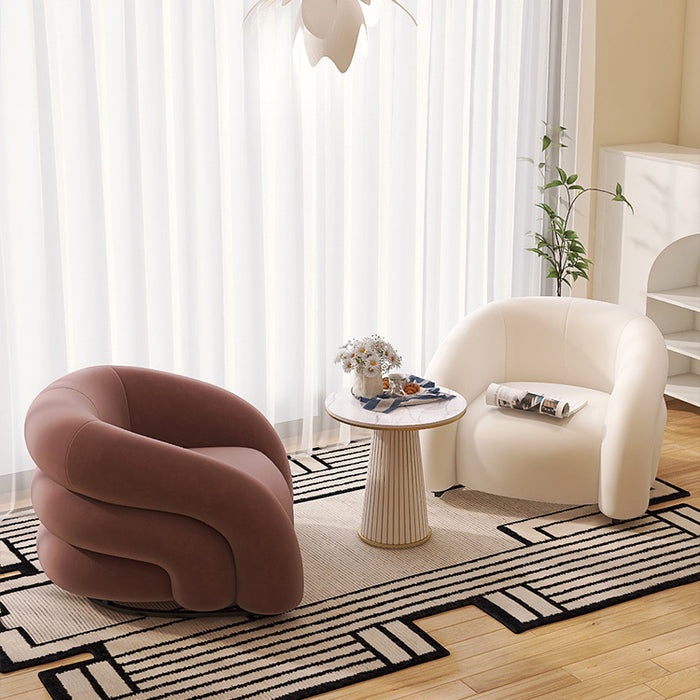 A styled interior scene with two upholstered accent chairs, a small round table, a rug, and sheer curtains in a bright room. The lefng.