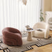 A styled interior scene with two upholstered accent chairs, a small round table, a rug, and sheer curtains in a bright room. The lefng.
