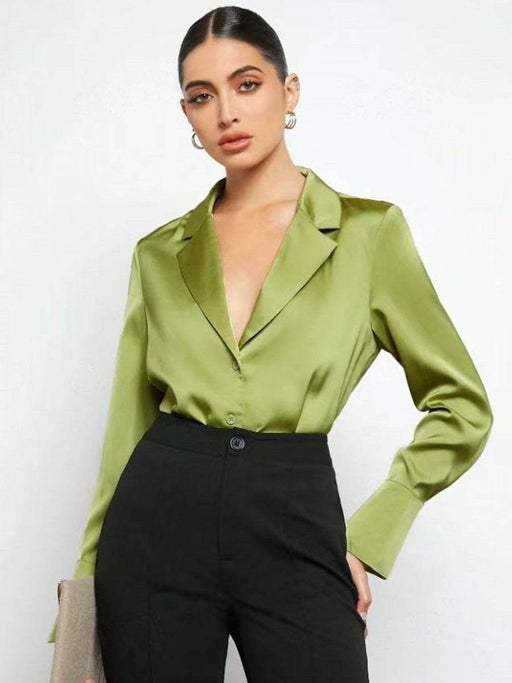 Woman wearing a green satin blouse and black pants against a white background